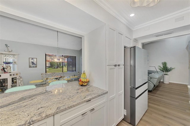 kitchen with plenty of natural light, white cabinets, refrigerator, and light stone countertops