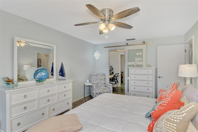 bedroom with ceiling fan, a barn door, and carpet