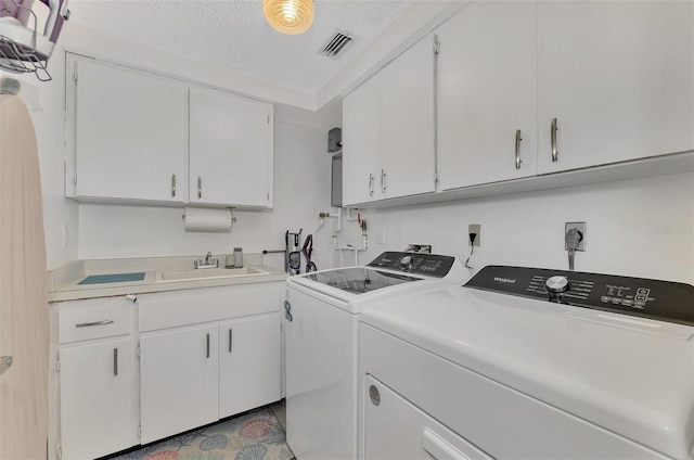 laundry room featuring separate washer and dryer, cabinets, sink, and a textured ceiling