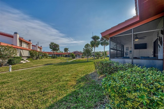 view of yard featuring ceiling fan and a sunroom