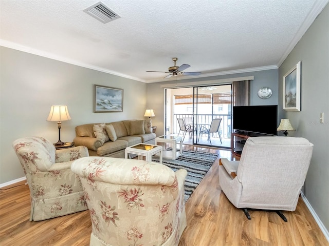 living room with ceiling fan, ornamental molding, a textured ceiling, and light wood-type flooring