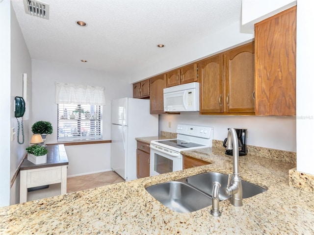 kitchen featuring light tile patterned floors, white appliances, a textured ceiling, and sink