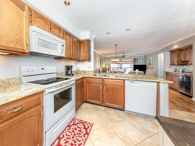 kitchen featuring kitchen peninsula, ornamental molding, white appliances, sink, and wine cooler