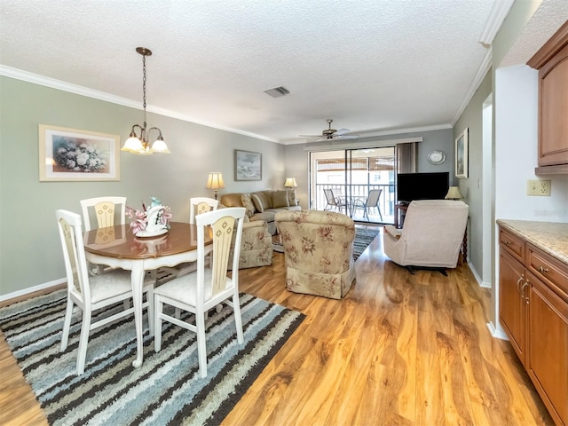 dining space with ceiling fan with notable chandelier, a textured ceiling, and light wood-type flooring