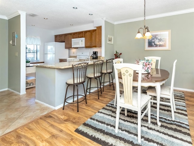 dining space with crown molding, light hardwood / wood-style floors, a textured ceiling, and an inviting chandelier