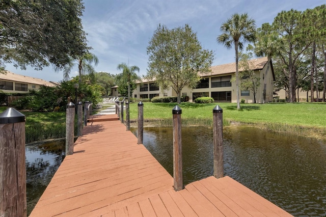 view of dock with a water view and a yard