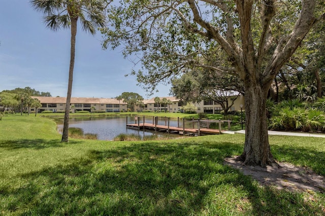 view of dock with a lawn and a water view