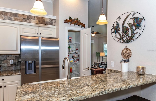 kitchen with dark stone counters, decorative light fixtures, stainless steel fridge with ice dispenser, and white cabinets