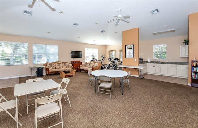 dining room with sink, light colored carpet, and ceiling fan