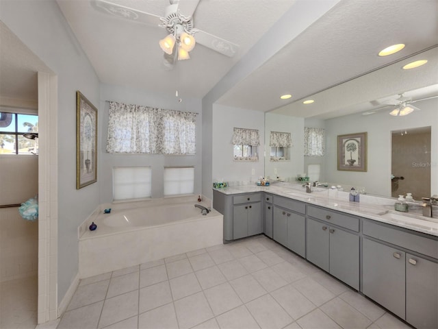 bathroom with a bathing tub, vanity, a textured ceiling, and tile patterned flooring