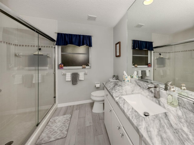 bathroom with vanity, toilet, an enclosed shower, and a textured ceiling