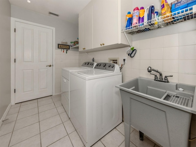 washroom featuring washer and dryer, light tile patterned floors, cabinets, and sink