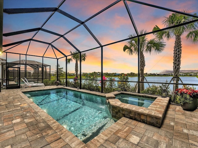 pool at dusk with a water view, a patio, glass enclosure, and an in ground hot tub