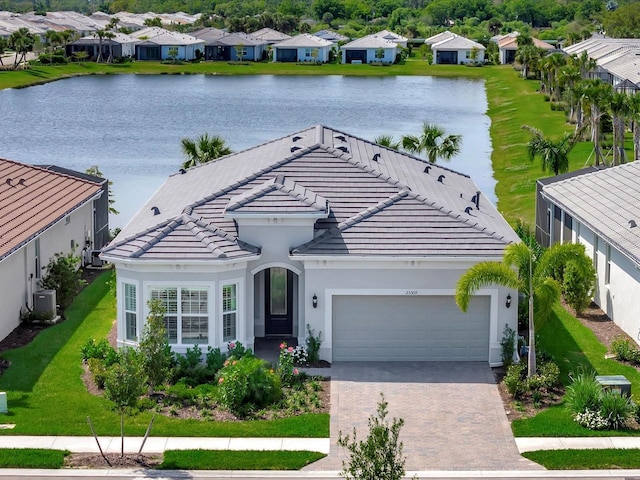 view of front of house featuring a front lawn, a garage, central air condition unit, and a water view