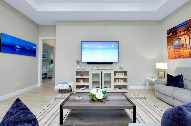 living room featuring a raised ceiling and light hardwood / wood-style flooring