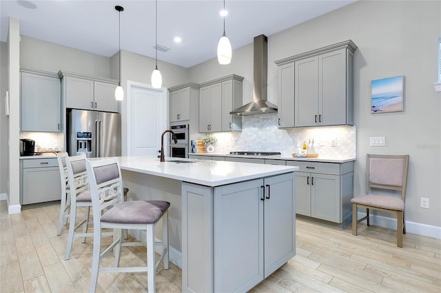 kitchen with gray cabinets, stainless steel appliances, and wall chimney range hood