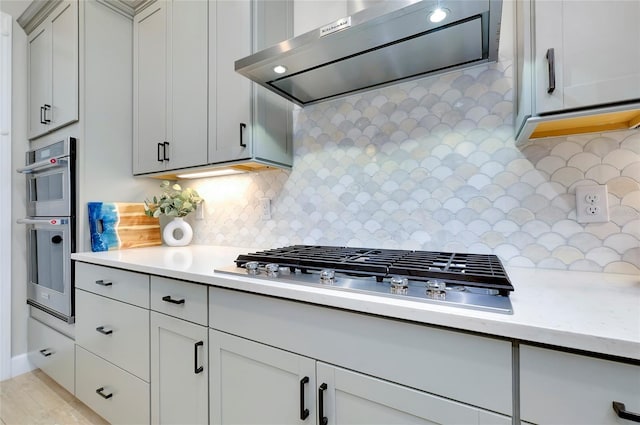 kitchen with exhaust hood, backsplash, and stainless steel appliances