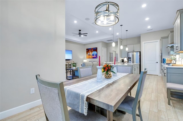 dining room featuring ceiling fan, a raised ceiling, and light hardwood / wood-style floors