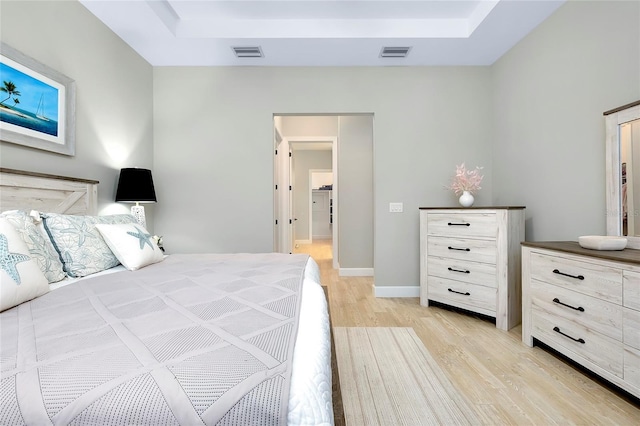 bedroom with a tray ceiling and light hardwood / wood-style flooring