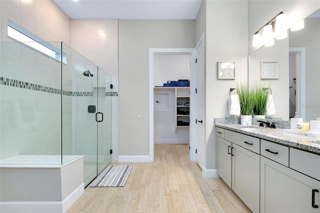 bathroom featuring hardwood / wood-style flooring, a shower with door, and vanity