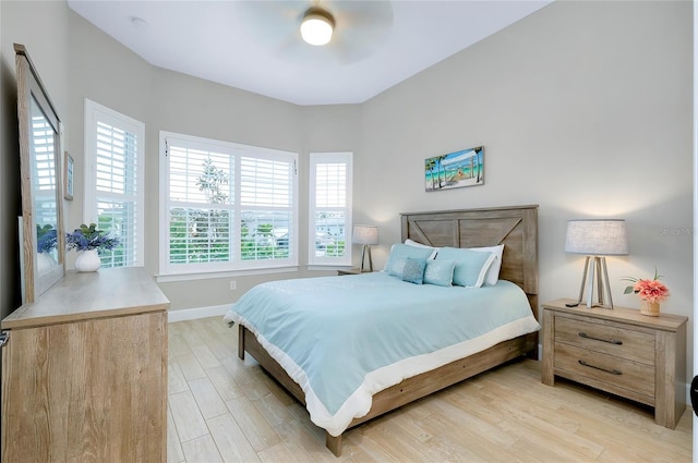 bedroom with ceiling fan, light hardwood / wood-style flooring, and multiple windows