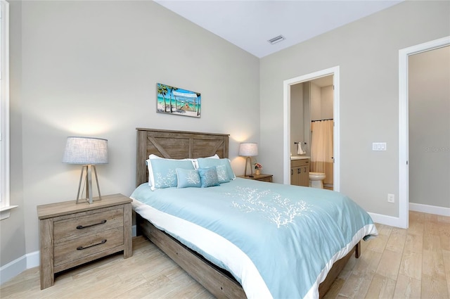 bedroom with ensuite bath and light wood-type flooring