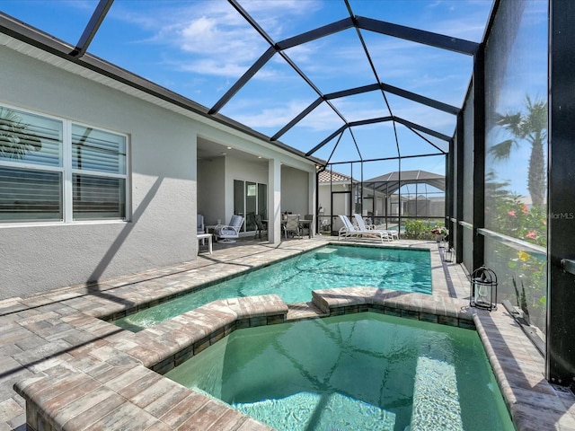 view of pool with a patio area, glass enclosure, and an in ground hot tub