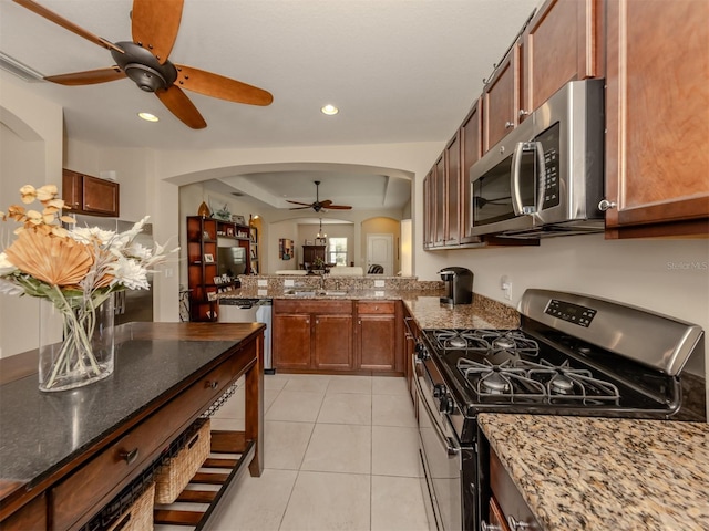 kitchen with stainless steel appliances, stone countertops, light tile patterned flooring, and sink