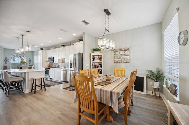 dining area with plenty of natural light, light wood-type flooring, and an inviting chandelier