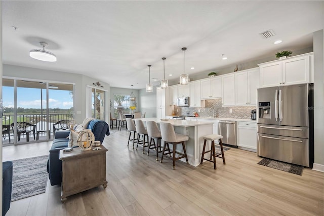 kitchen featuring appliances with stainless steel finishes, hanging light fixtures, a kitchen breakfast bar, a center island, and white cabinets