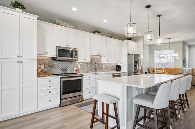 kitchen with white cabinetry, hanging light fixtures, a center island, and appliances with stainless steel finishes