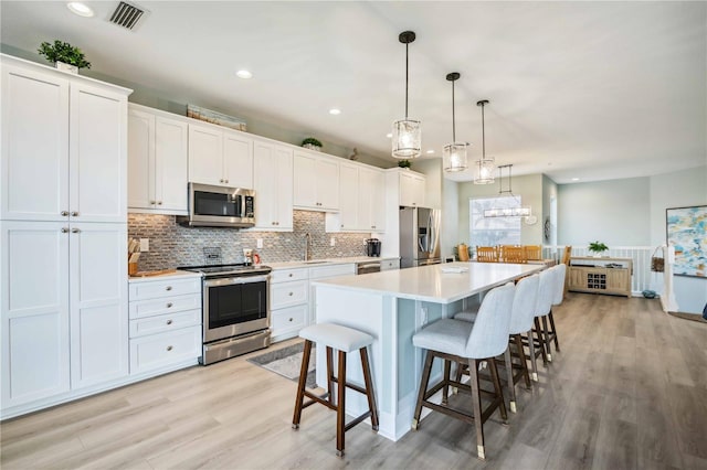 kitchen with stainless steel appliances, a center island, and white cabinets