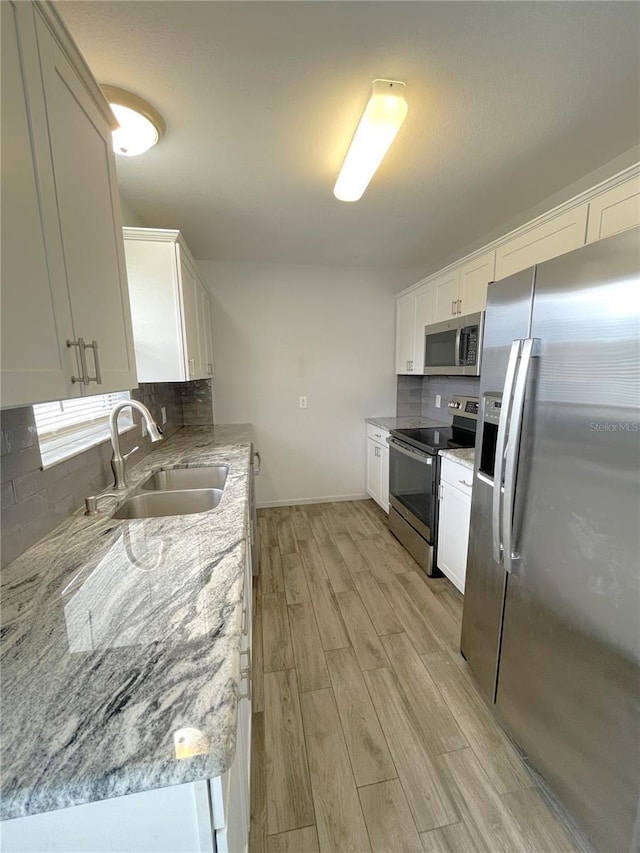 kitchen featuring light stone countertops, white cabinetry, sink, and appliances with stainless steel finishes