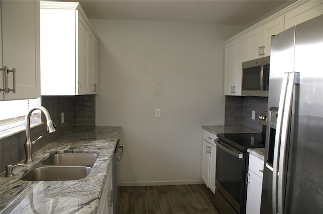 kitchen with sink, tasteful backsplash, light stone counters, white cabinets, and appliances with stainless steel finishes