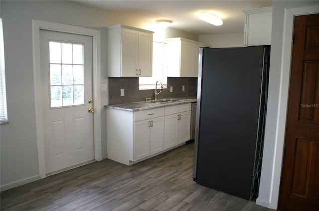 kitchen with decorative backsplash, stainless steel fridge, white cabinetry, and sink