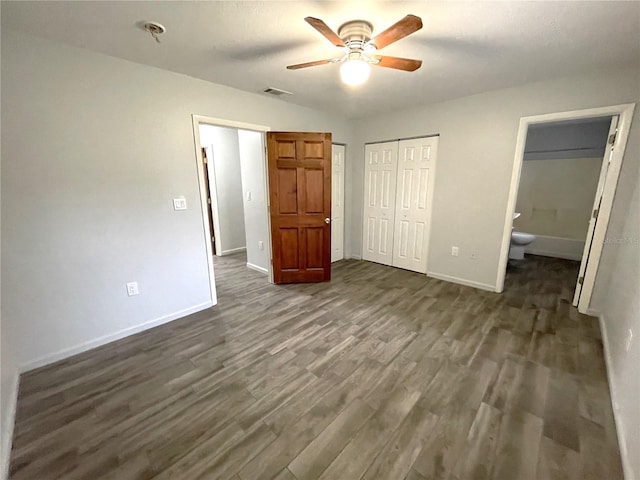 unfurnished bedroom with a closet, ensuite bath, ceiling fan, and dark hardwood / wood-style flooring