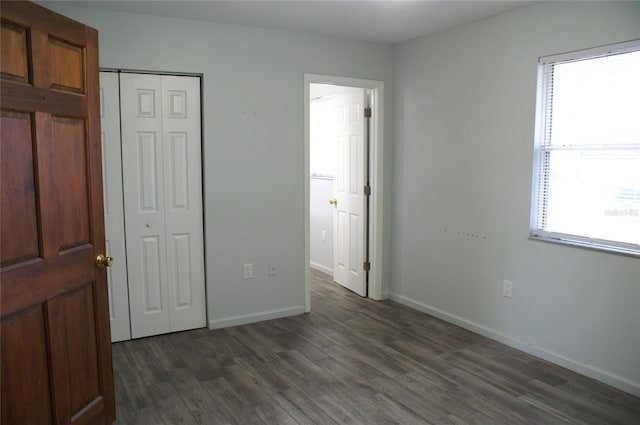 unfurnished bedroom with dark wood-type flooring and a closet