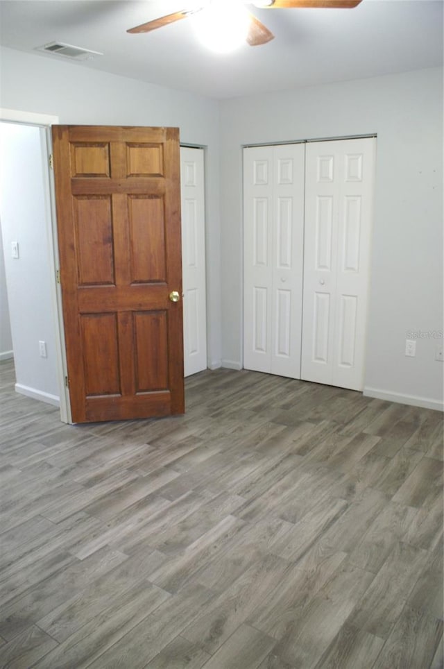 unfurnished bedroom featuring wood-type flooring, a closet, and ceiling fan