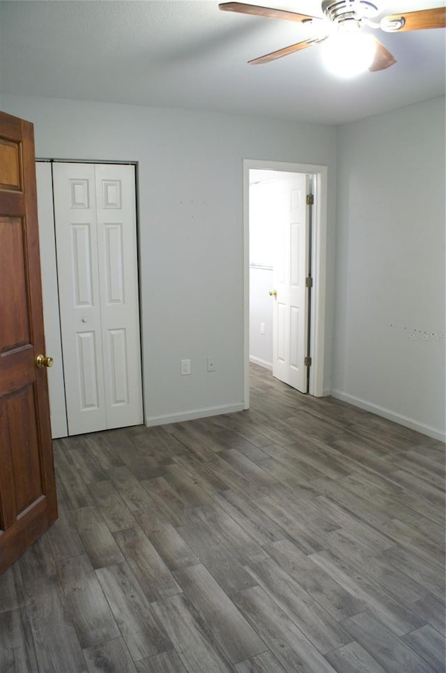 unfurnished bedroom featuring ceiling fan, dark wood-type flooring, and a closet