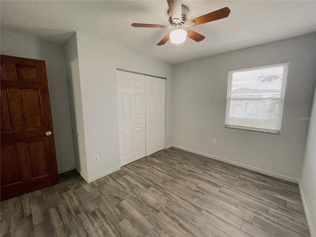 unfurnished bedroom with ceiling fan, a closet, and wood-type flooring