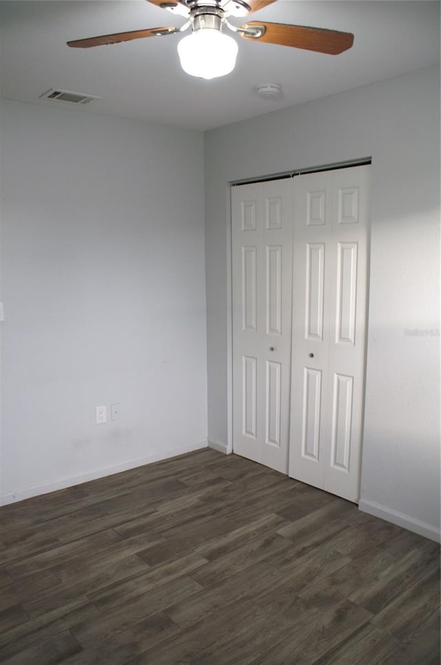 unfurnished bedroom with ceiling fan, dark hardwood / wood-style floors, and a closet