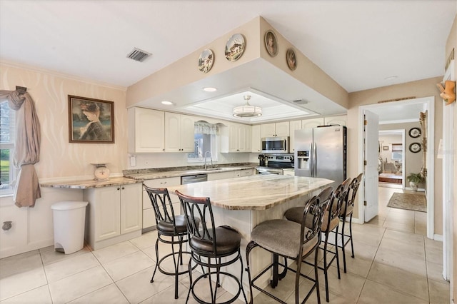 kitchen featuring stainless steel appliances, sink, a raised ceiling, a breakfast bar, and light tile patterned floors