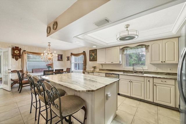 kitchen featuring a kitchen island, sink, hanging light fixtures, a raised ceiling, and light tile patterned floors