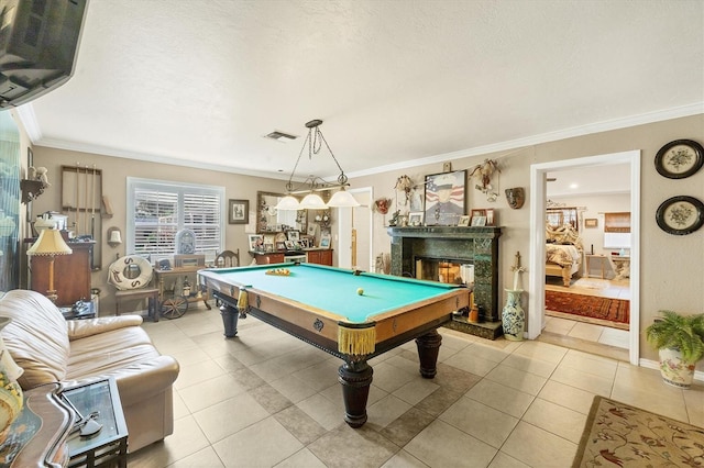 recreation room featuring a textured ceiling, pool table, a fireplace, light tile patterned floors, and crown molding