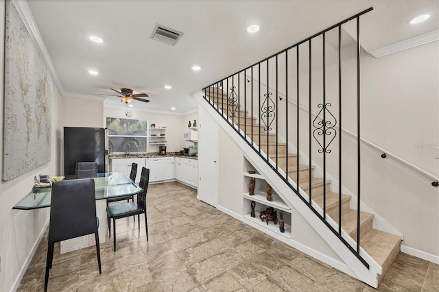 dining space with ceiling fan, crown molding, and sink