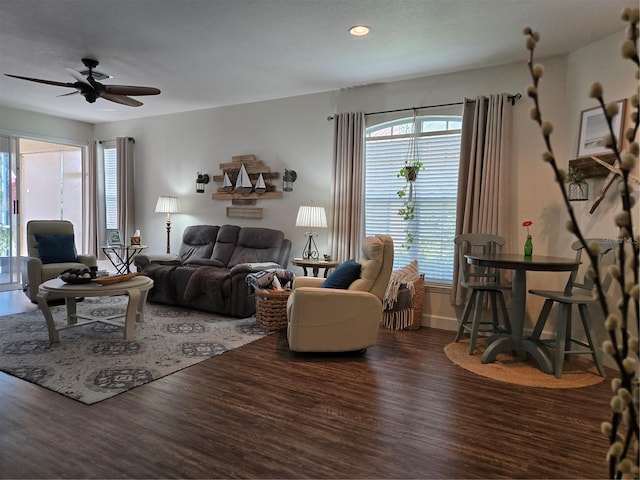 living room with plenty of natural light, ceiling fan, and dark wood-type flooring