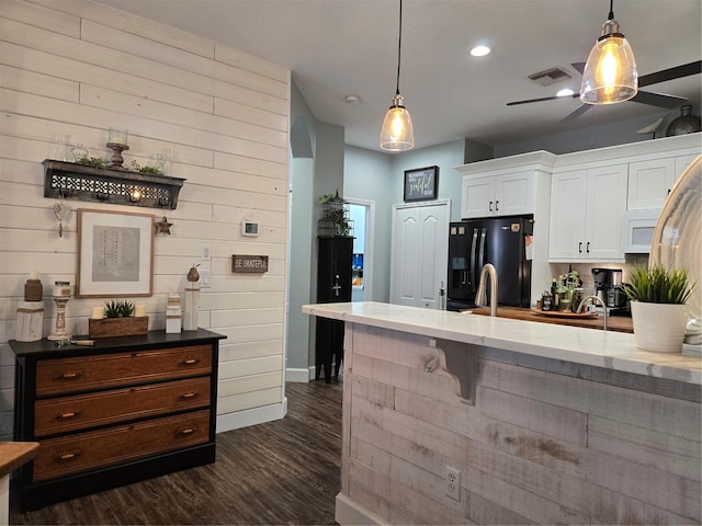 kitchen featuring wooden walls, white cabinetry, dark wood-type flooring, and black refrigerator with ice dispenser