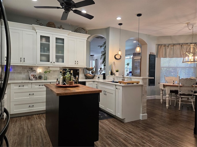 kitchen featuring butcher block countertops, white cabinets, a kitchen island, and hanging light fixtures