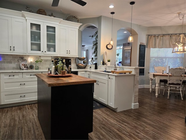 kitchen with a center island, sink, kitchen peninsula, decorative light fixtures, and white cabinets