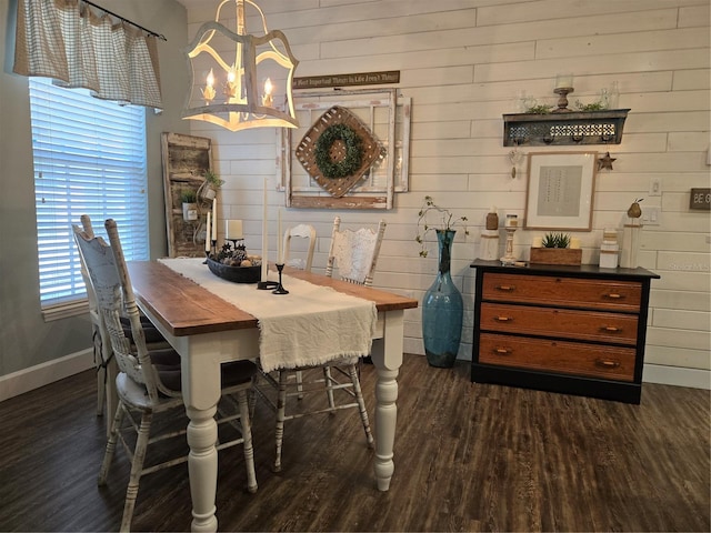 dining room featuring dark hardwood / wood-style flooring, wooden walls, and an inviting chandelier